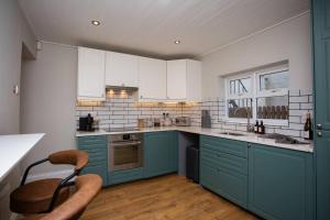 una cocina con armarios azules y una silla. en The Saint George en High Heaton
