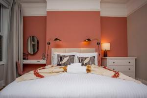1 dormitorio con 1 cama blanca grande y paredes de color naranja en The Saint George en High Heaton
