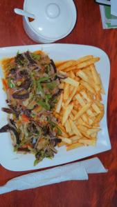 un plato de comida con papas fritas en una mesa en DEUDJUI HOTEL, en Bafang