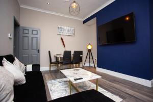 Elle comprend un salon doté d'un mur bleu et d'une télévision. dans l'établissement Modern Interior Spacious Four Bedroom Apartment, à Westoe