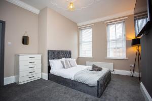 - une chambre avec un lit, une commode et des fenêtres dans l'établissement Modern Interior Spacious Four Bedroom Apartment, à Westoe