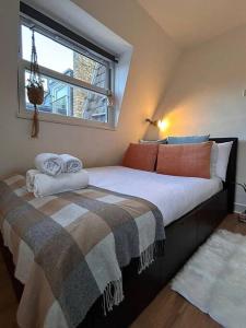 - une chambre avec un lit doté d'oreillers et d'une fenêtre dans l'établissement Charming Fulham flat, à Londres