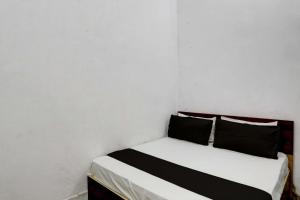 a white room with a bed with two black pillows at Super OYO New River View in Jhājhar
