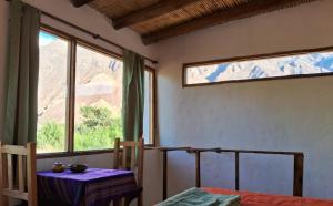 a room with a bed and a table and windows at Cabañas APU in Maimará