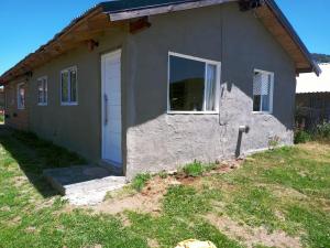 una pequeña casa con una pared de piedra en El Llanqui en San Carlos de Bariloche