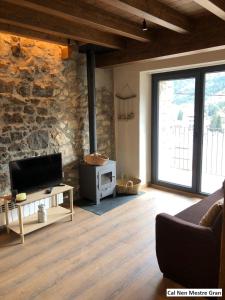 a living room with a tv and a stone wall at Cal Nen Mestre in Martinet