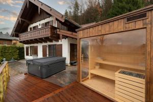 une grande terrasse avec un bain à remous et une maison dans l'établissement Luxus Alpenparadies nahe Salzburg Sauna & Whirlpool, à Adnet