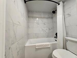 a white bathroom with a tub and a toilet at The Hotel Pendleton, Trademark Collection by Wyndham in Pendleton +33 photos