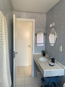 y baño con lavabo y espejo. en Residencial Ametista - 250 metros do mar, en Florianópolis