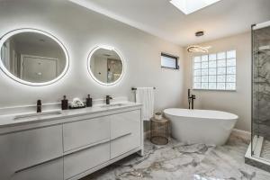 a bathroom with a tub and sink and two mirrors at Lauderdale By The Sea home in Fort Lauderdale