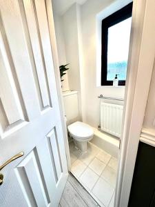 a white bathroom with a toilet and a window at Stylish 3 Bed House in Greenhithe in Greenhithe