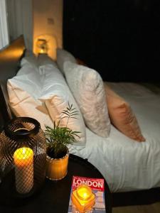 Una cama con almohadas y una mesa con una vela. en Cosy studio on the Thames, en Londres