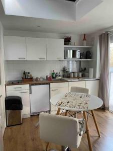 a kitchen with white cabinets and a table and chairs at Cosy studio on the Thames in London
