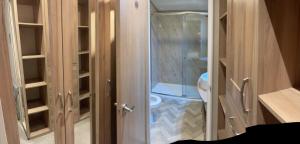 a bathroom with a toilet and a glass door at Loubet Extra Large Lodge in Auchterarder