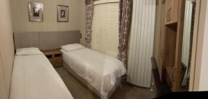 two beds in a small room with a window at Loubet Extra Large Lodge in Auchterarder