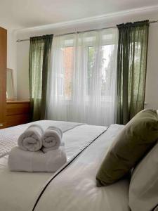 sypialnia z 2 ręcznikami na łóżku z oknem w obiekcie Ealing Broadway bright flat w mieście Ealing
