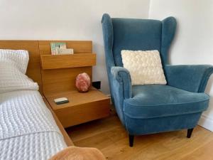 a blue chair with a pillow next to a bed at Ealing Broadway bright flat in Ealing