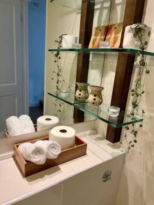 een badkamer met een plank met handdoeken en een spiegel bij Ealing Broadway bright flat in Ealing