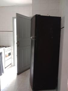 - un réfrigérateur noir dans une cuisine à côté d'une porte dans l'établissement Casa de Praia em São Pedro da Aldeia, à São Pedro da Aldeia