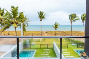 einen Balkon mit Blick auf den Strand und die Palmen in der Unterkunft Portal beira mar (casa) in Tamandaré