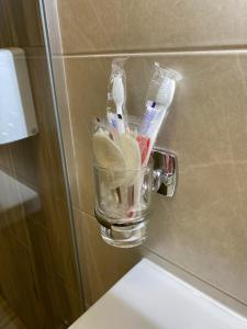 a glass cup holding toothbrushes and toothpaste on a wall at VATRA HOTEL in Ternopilʼ