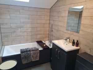 a bathroom with a bath tub and a sink and a mirror at Cullen Holiday Home in Cullen