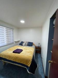 a bedroom with a bed with a yellow blanket at Cabaña con vista al Lago in Ranco
