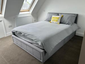 a bedroom with a bed with a grey bedspread and a yellow pillow at Stunning Modern, Brand-New 1 Bed Flat Only 15 Mins To Central London in The Hyde