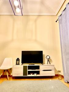 - un salon avec une télévision à écran plat dans un centre de divertissement blanc dans l'établissement Amplio apartamento con dos patios y aparcamiento privado, à Gijón
