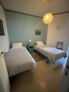 a bedroom with two beds and a light fixture at Daloba House in Costa da Caparica