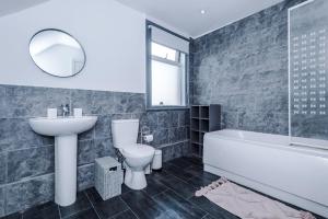 a bathroom with a sink and a tub and a toilet at Knutsford Road Moreton Wirral 3 bedroom 1 bathroom duplex apartment private parking by Rework Accommodation in Moreton
