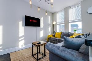 a living room with a couch and a tv on a wall at Knutsford Road Moreton Wirral 3 bedroom 1 bathroom duplex apartment private parking by Rework Accommodation in Moreton