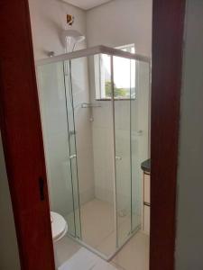 y baño con ducha de cristal y aseo. en Agradável apartamento perto da praia, en Florianópolis