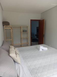 a bedroom with a large white bed with two pillows at Agradável apartamento perto da praia in Florianópolis