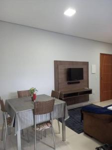 una sala da pranzo con tavolo, sedie e TV di Agradável apartamento perto da praia a Florianópolis