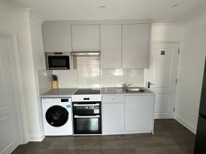 una cucina con lavatrice e lavatrice di Stunning Modern, Brand-New 1 Bed Flat Only 15 Mins To Central London a The Hyde