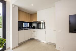 a kitchen with white cabinets and stainless steel appliances at Varkiza Luxury Suites by Raise in Vari