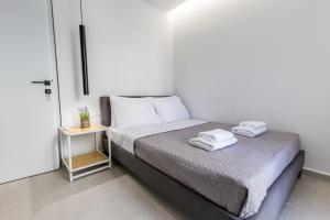 a bedroom with a bed with two towels on it at Varkiza Luxury Suites by Raise in Vari