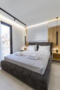 Varkiza Luxury Suites في فاري: غرفة نوم بسرير كبير عليها منشفتين