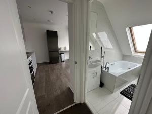 un bagno bianco con vasca e lavandino di Stunning Modern, Brand-New 1 Bed Flat Only 15 Mins To Central London a The Hyde