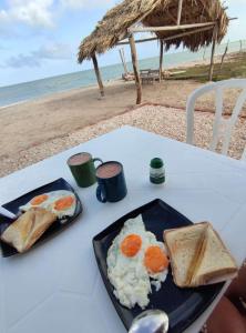 habitación frente al mar في Mayapo: طبق من البيض والخبز المحمص على طاولة على الشاطئ