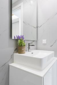 a white bathroom with a sink and a mirror at Varkiza Luxury Suites by Raise in Vari