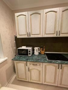 une cuisine avec des placards en bois et un four micro-ondes sur un comptoir dans l'établissement Apartamenty u Ksyu, à Pizunda