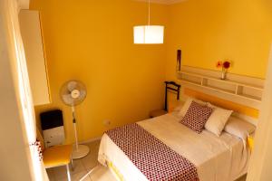 um quarto amarelo com uma cama e uma ventoinha em Departamento Luminoso a metros del Mar en pleno Centro em Mar del Plata