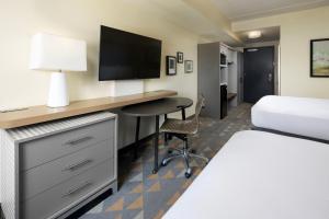 a hotel room with a bed and a desk with a television at The Scenic Hotel at Biltmore Village in Asheville