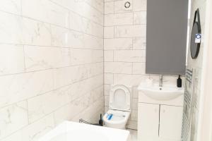 a white bathroom with a toilet and a sink at Beautiful 5 single bedroom house in Dagenham