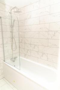 a white bathroom with a shower and a tub at Beautiful 5 single bedroom house in Dagenham