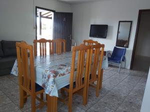 a dining room table and chairs with a table and a television at Apto com terraço coberto in Arroio do Sal