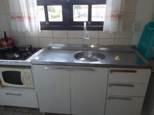 a small kitchen with a sink and a stove at Apto com terraço coberto in Arroio do Sal