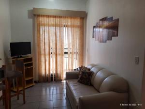 een woonkamer met een leren bank en een televisie bij Apto confortável, acolhedor e bem localizado in Campos dos Goytacazes